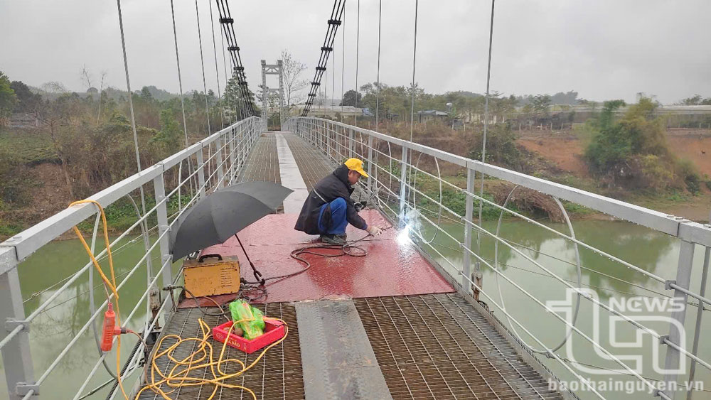 Công nhân thi công sửa chữa 1 số vị trí mặt cầu treo bị cong vênh, hư hỏng.
