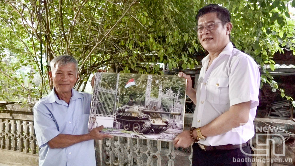Ông Ngô Mạnh Hùng, Chủ tịch Liên đoàn Lao động TP. Sông Công (bên phải) tặng ông Ngô Quang Tỵ bức tranh mô phỏng chiếc xe tăng của Quân giải phóng húc đổ cổng Dinh Độc Lập.