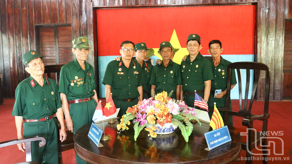 Cựu chiến binh huyện Củ Chi (TP. Hồ Chí Minh) chụp ảnh bên chiếc bàn tròn diễn ra Hội nghị 4 bên tại Nhà Giao tế Lộc Ninh năm 1973.