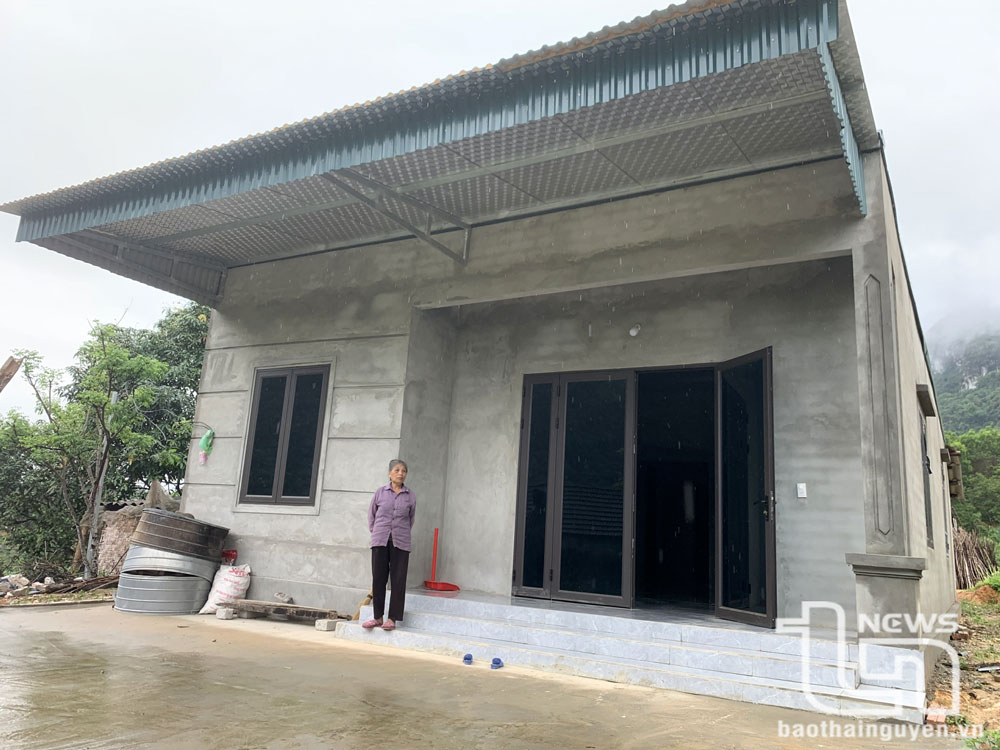 Bà Ngô Thị Càn, ở xóm Làng Giai, xã La Hiên (Võ Nhai) bên ngôi nhà mới được hỗ trợ xây dựng từ phong trào xóa nhà tạm, nhà dột nát.