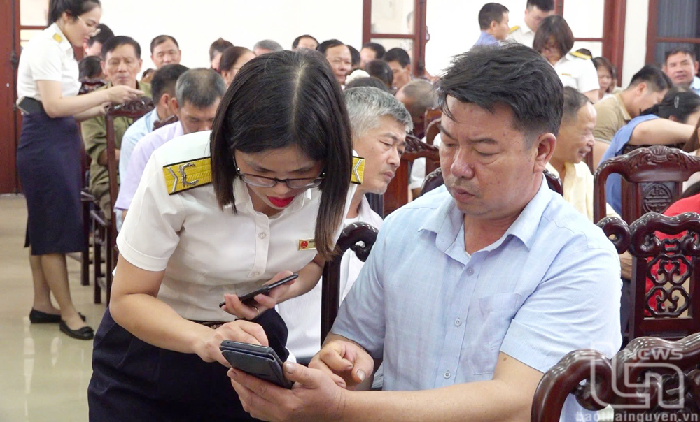 Cán bộ thuế truyền thông chính sách đến các hộ kinh doanh qua ứng dụng trên điện thoại.