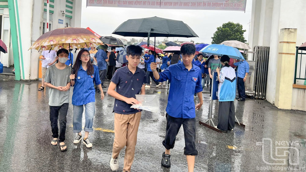 Sáng 5-6 do thời tiết mưa, đội thanh niên tình nguyện che ô hỗ trợ thí sinh vào phòng thi.