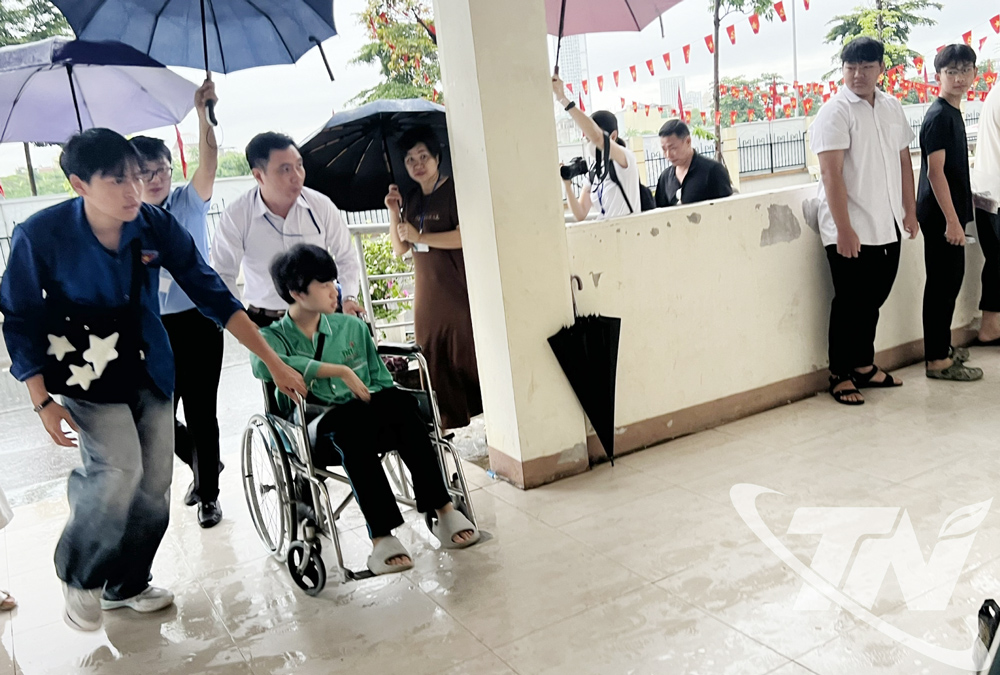 Vũ Lâm Hùng được cán bộ coi thi, nhân viên y tế, thanh niên tình nguyện hỗ trợ di chuyển vào phòng thi.