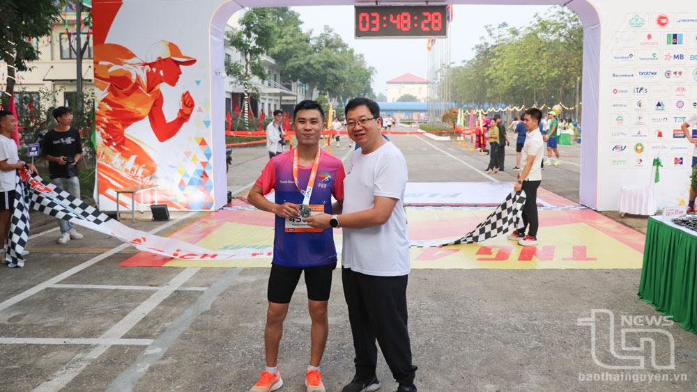 Đại diện Ban Tổ chức trao huy chương cho vận động viên sau khi hoàn thành phần thi chạy bộ.