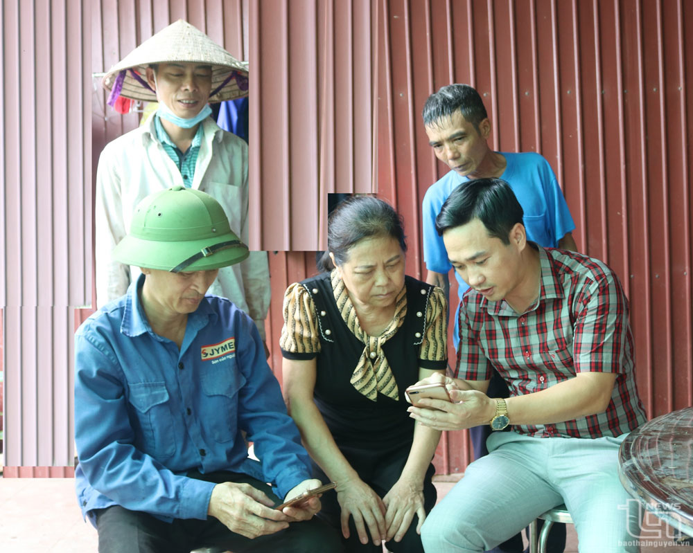 Anh Đới Duy Hồng (ngoài cùng bên phải), Phó Chủ tịch UBND thị trấn Hùng Sơn, Đại Từ, hướng dẫn người dân tìm hiểu nội dung Chỉ thị số 05-CT/TW về “Học tập và làm theo tư tưởng, đạo đức, phong cách Hồ Chí Minh” trên điện thoại thông minh.