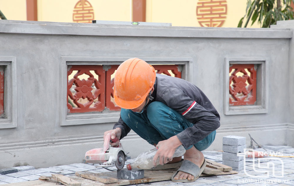 Các công nhân đo kích thước cẩn thận khi cắt đá lát nền sân để đảm bảo mỹ thuật và chất lượng công trình.
